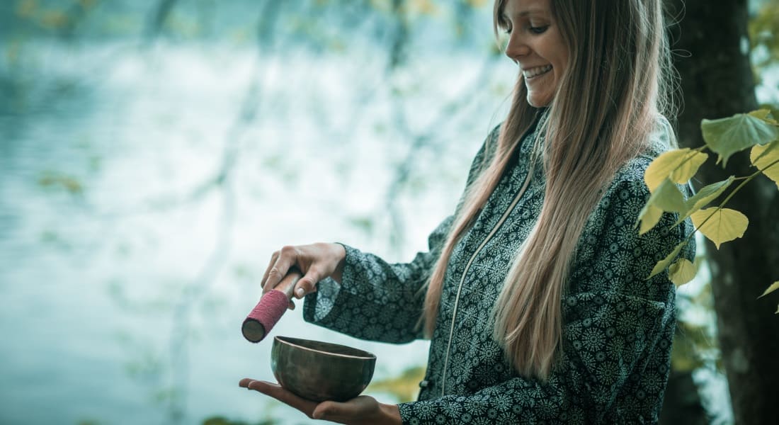 A smiling young woman using a singing bowl
