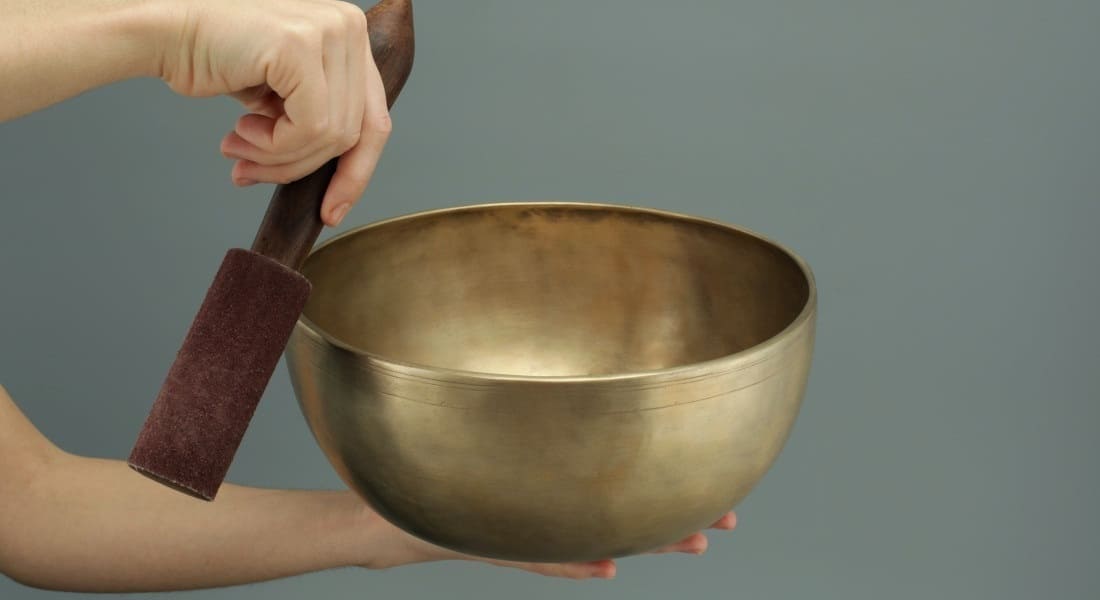 A Tibetan singing bowl held at arm's length with a mallet