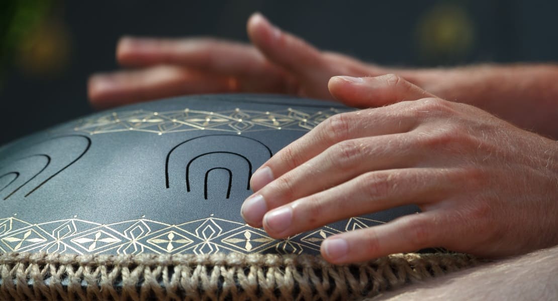 Two hands playing a tongue drum