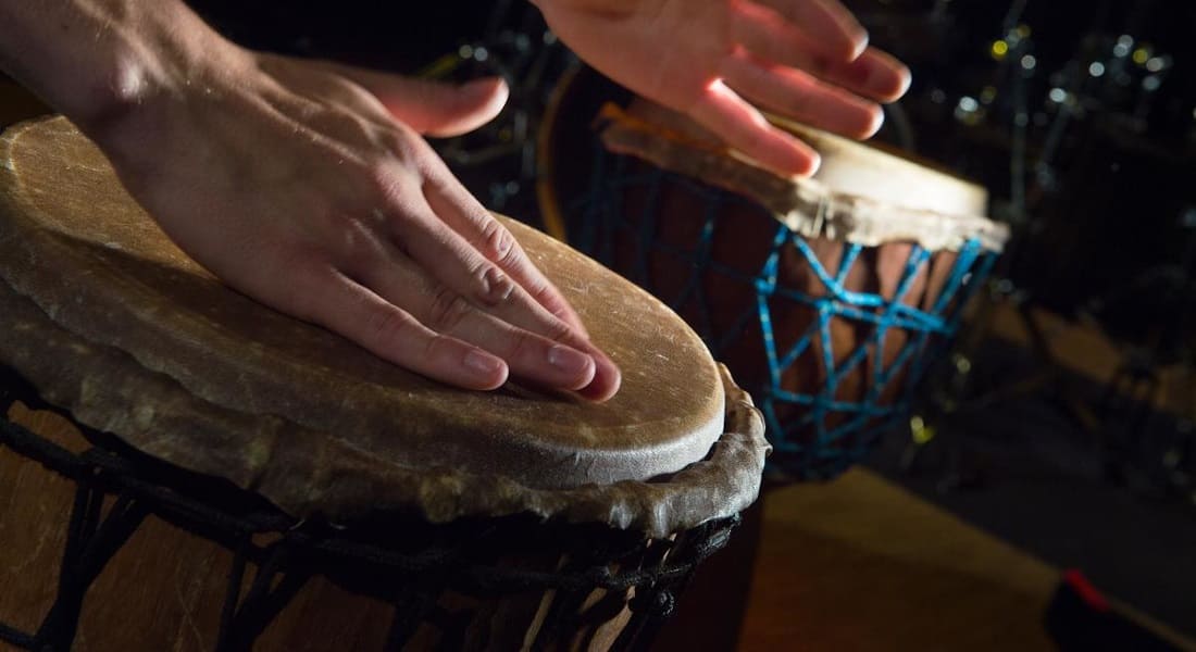 Two hands striking a traditional djembe