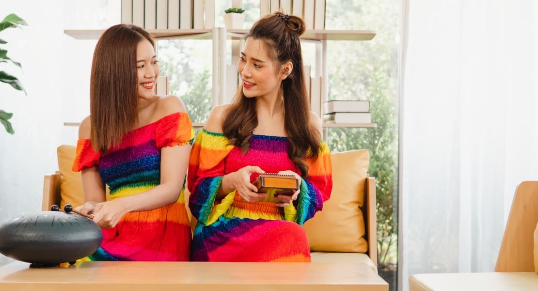 Two women, one playing a kalimba and the other a tongue drum