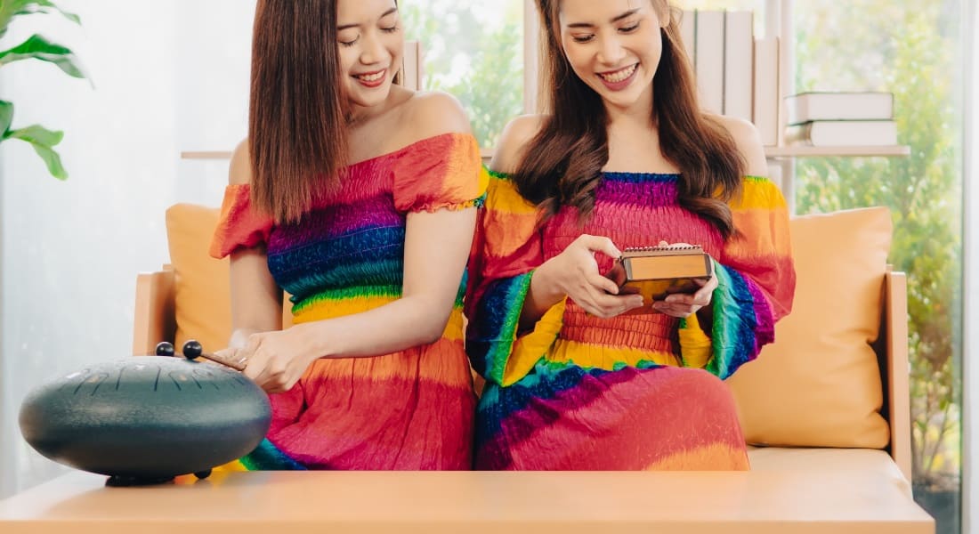Two women, one of them playing a tongue drum