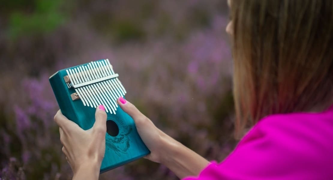 A woman seen from behind playing a blue kalimba