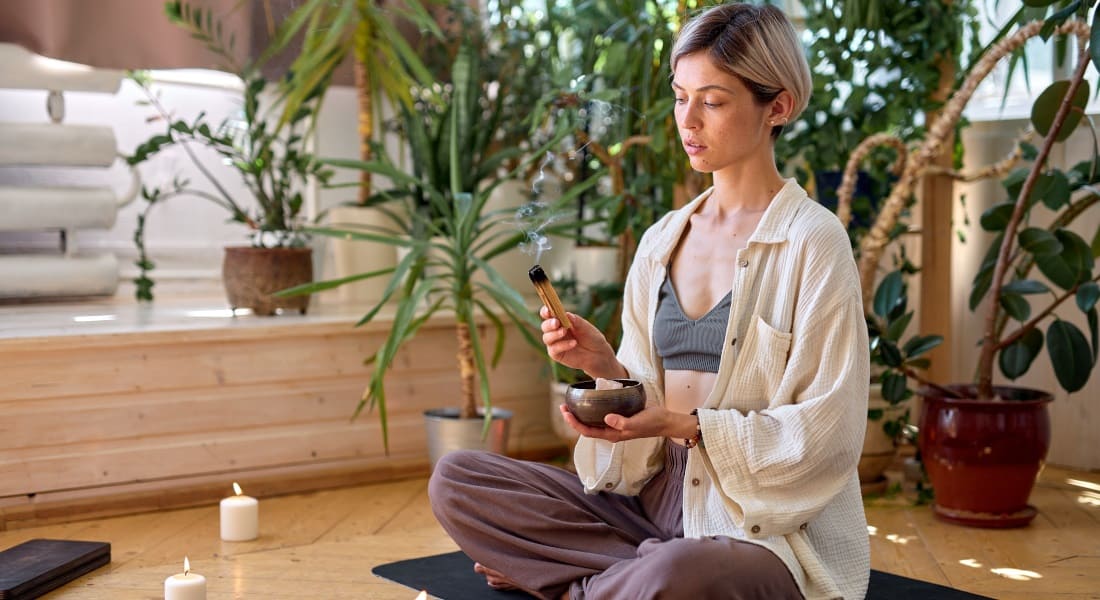 A woman sitting cross-legged holding a Tibetan singing bowl