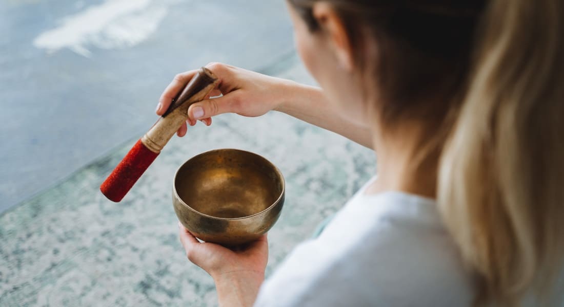 A woman seen from behind using a Tibetan singing bowl