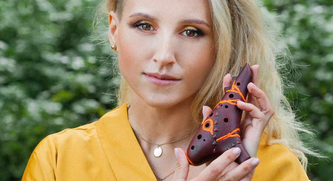 A woman holding a red ocarina in her hands