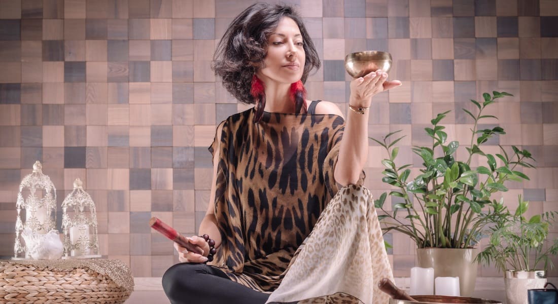 A woman holding a singing bowl in the palm of her hand