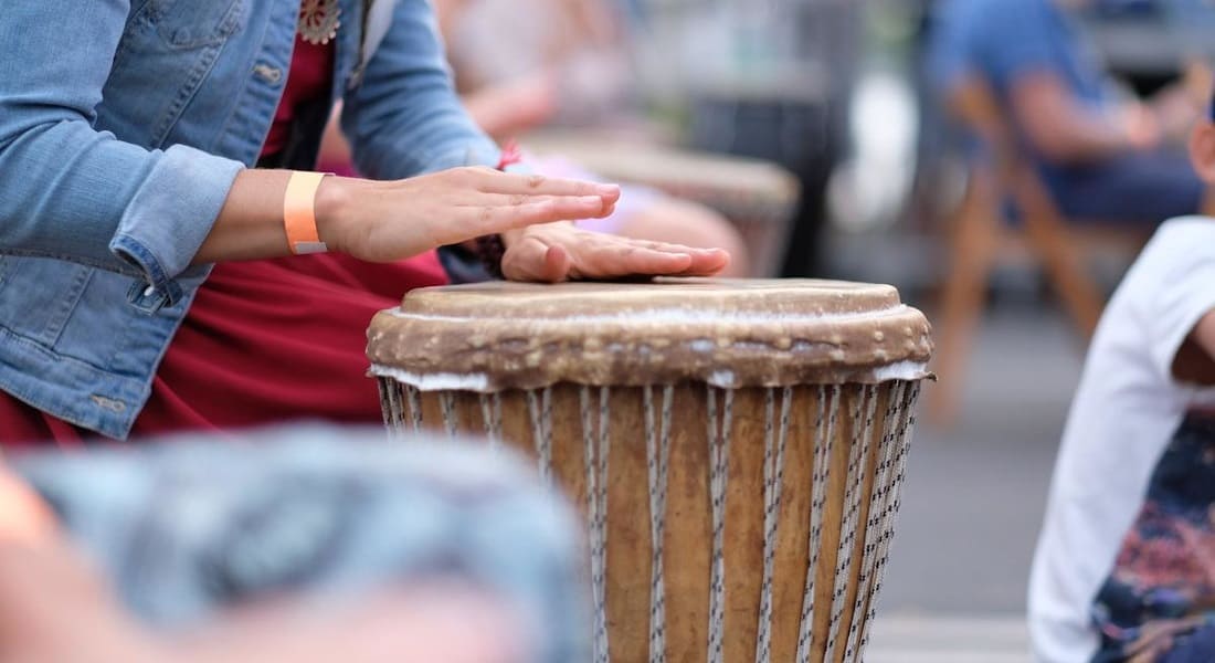 A woman in a denim jacket playing djembe