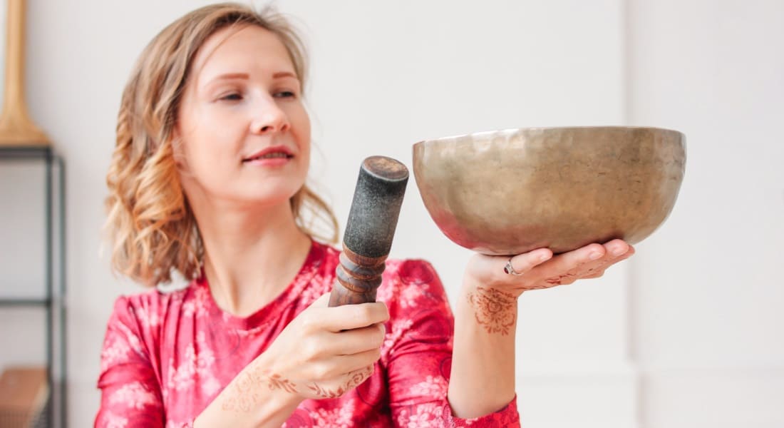 A woman in a pink dress with a Tibetan singing bowl