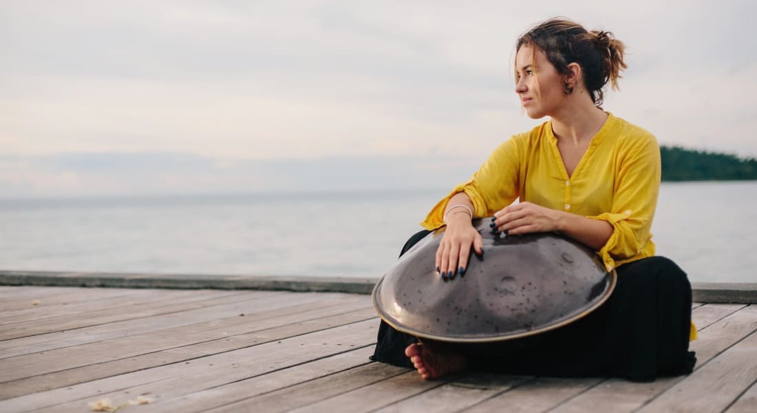 A woman looking at the horizon with a handpan