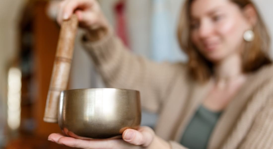 A woman meditating with a metal Tibetan singing bowl