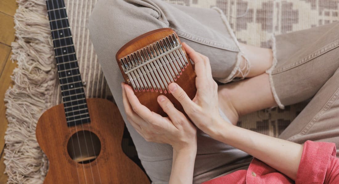 A woman playing a kalimba with a ukulele next to her