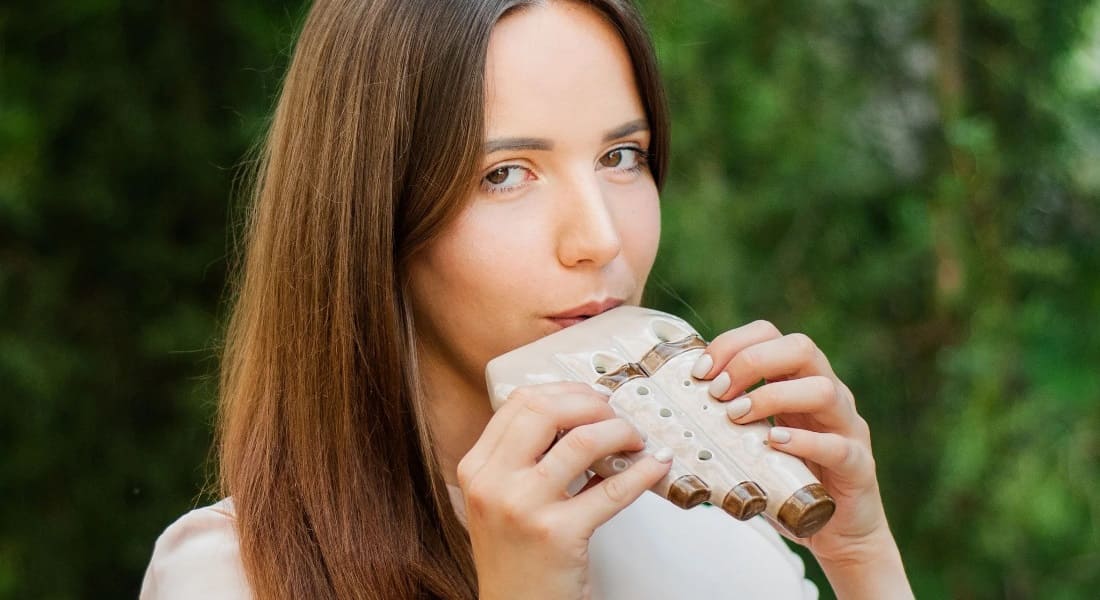 A woman playing a multi-chamber ocarina