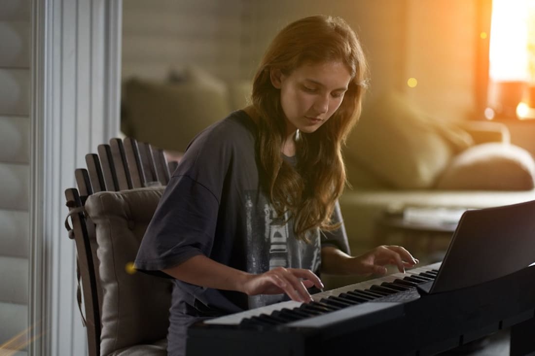A woman playing while seated at a digital piano