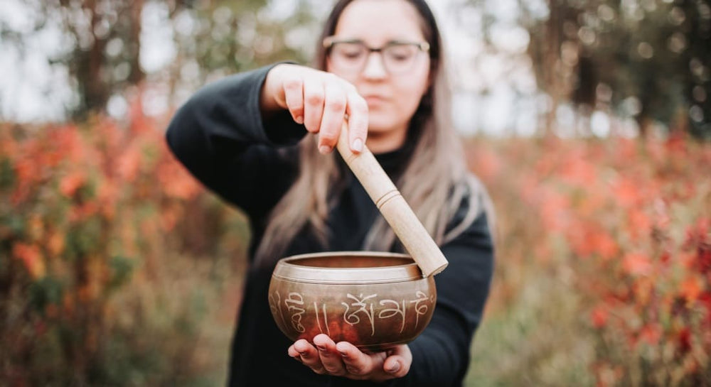A woman playing a singing bowl with a mallet