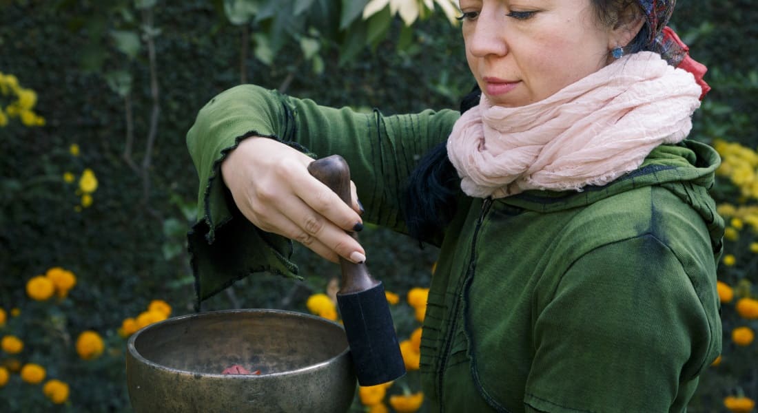 Woman playing a Tibetan singing bowl with a stick