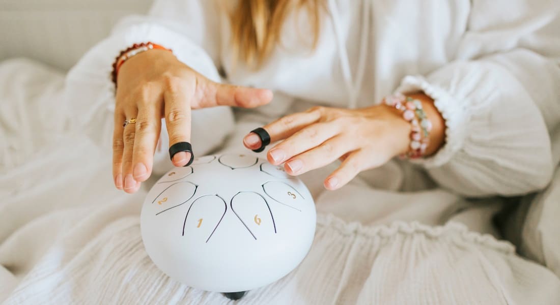A woman playing a tongue drum with finger protectors