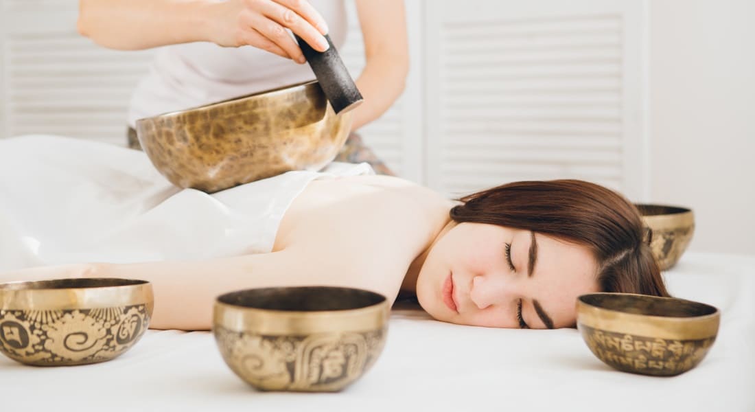 A woman lying on her stomach during a sound massage with Tibetan singing bowls