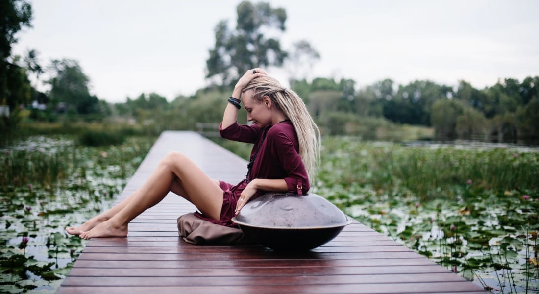 A woman sitting on a dock with a handpan