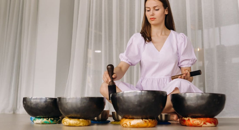 A woman surrounded by several Tibetan singing bowls set on cushions