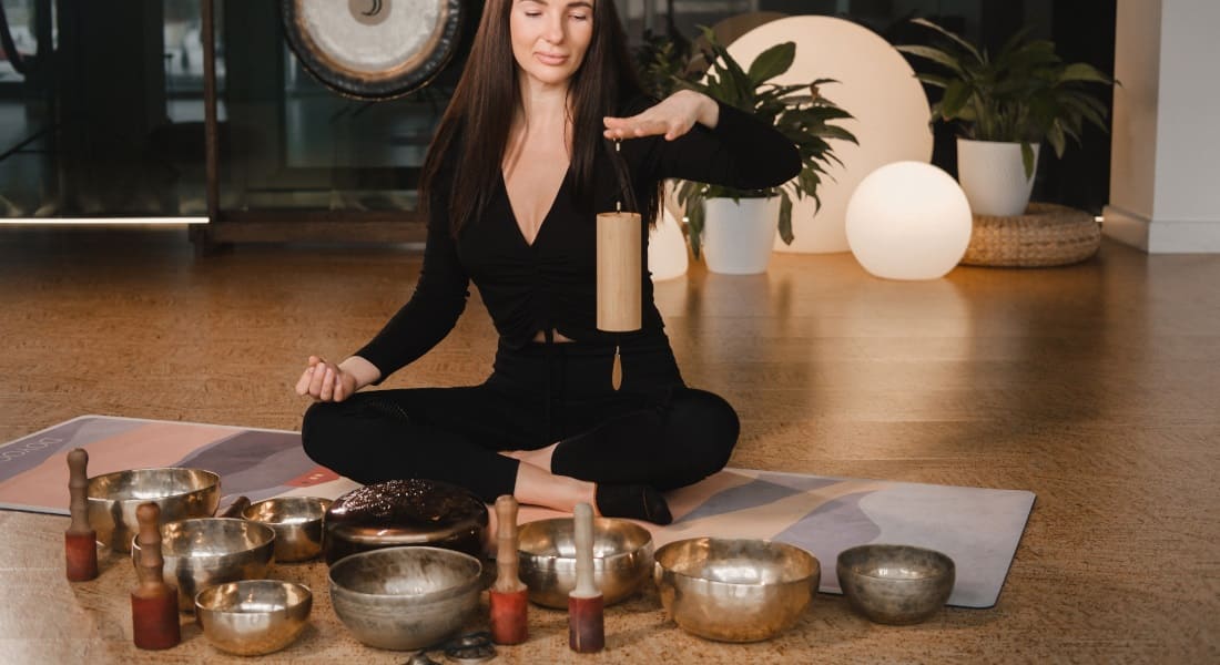 A woman with a chime surrounded by singing bowls