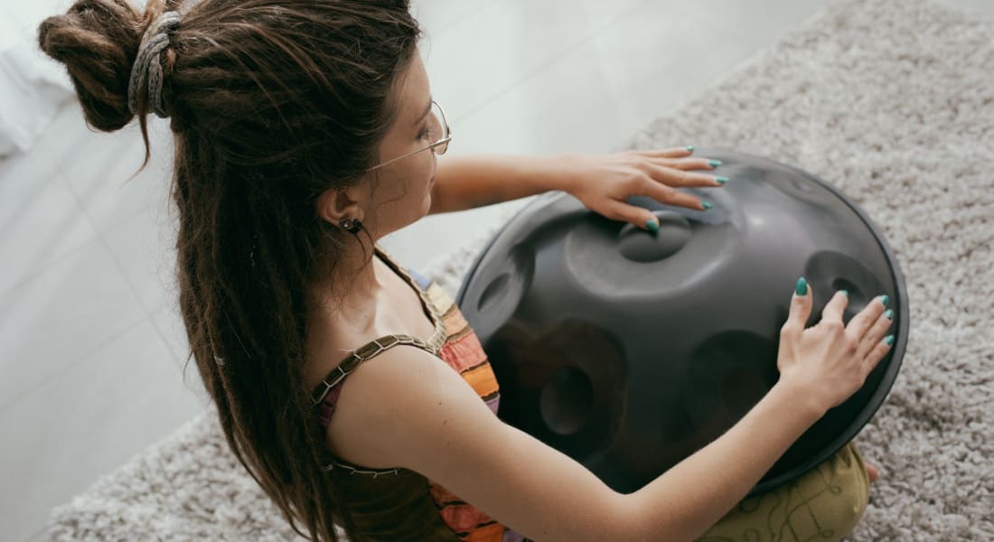 A woman with glasses playing the handpan