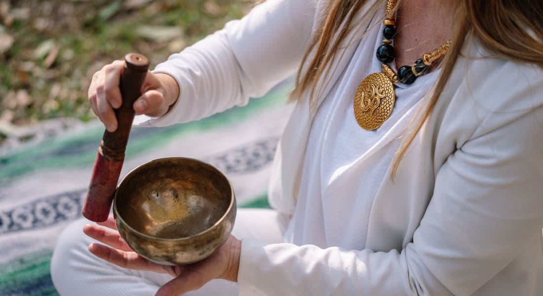 A woman with a pendant and a Tibetan singing bowl