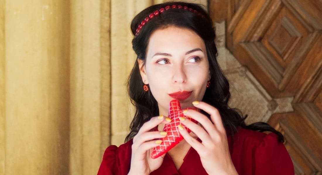 A woman in front of a wooden door holding a red ocarina