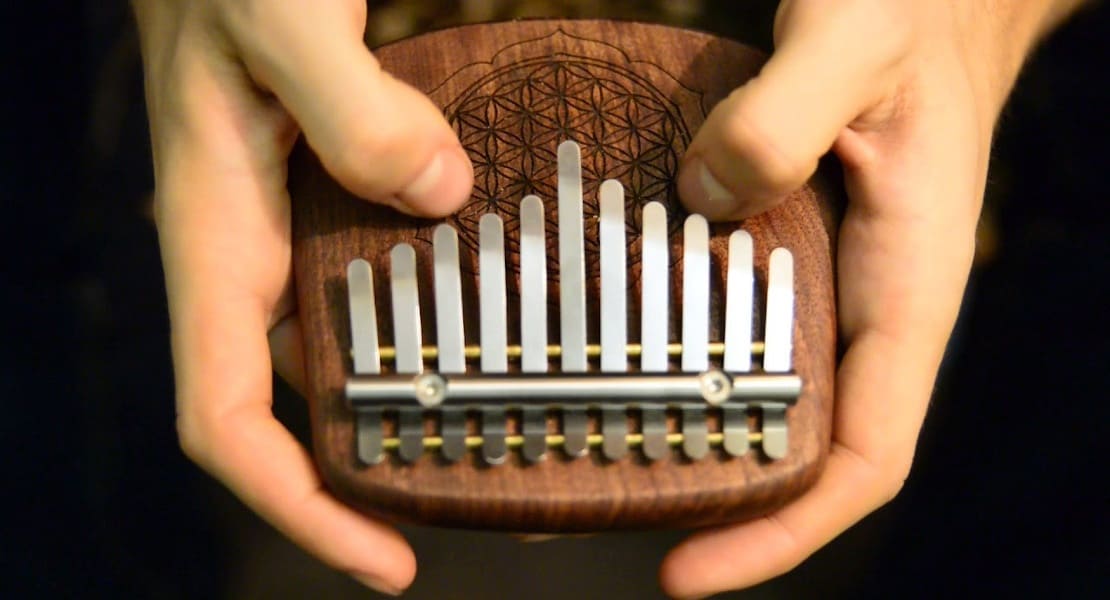 A wooden 10-tine kalimba held between two hands