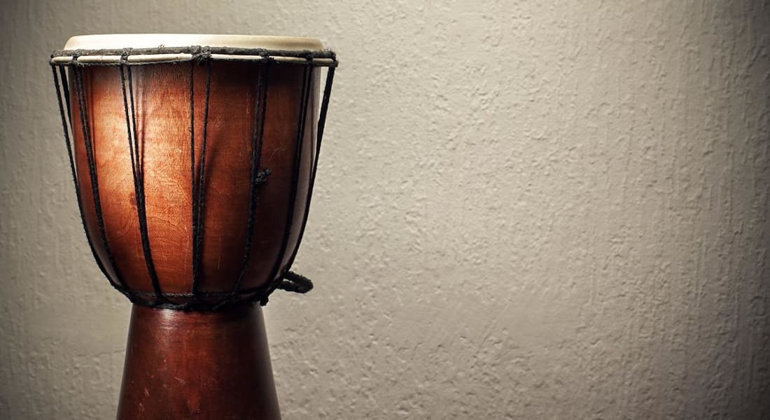 A wooden djembe with black ropes