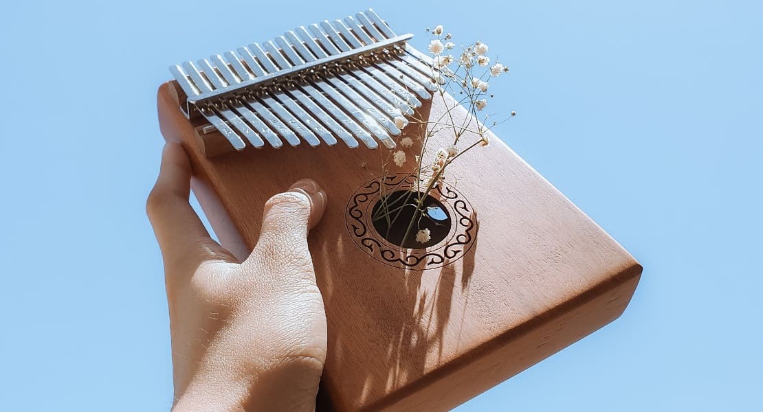 A wooden kalimba held up in the air by a hand