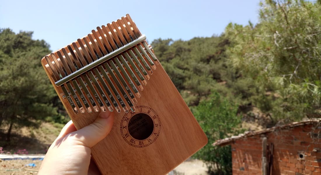 A brown wooden kalimba held in a hand