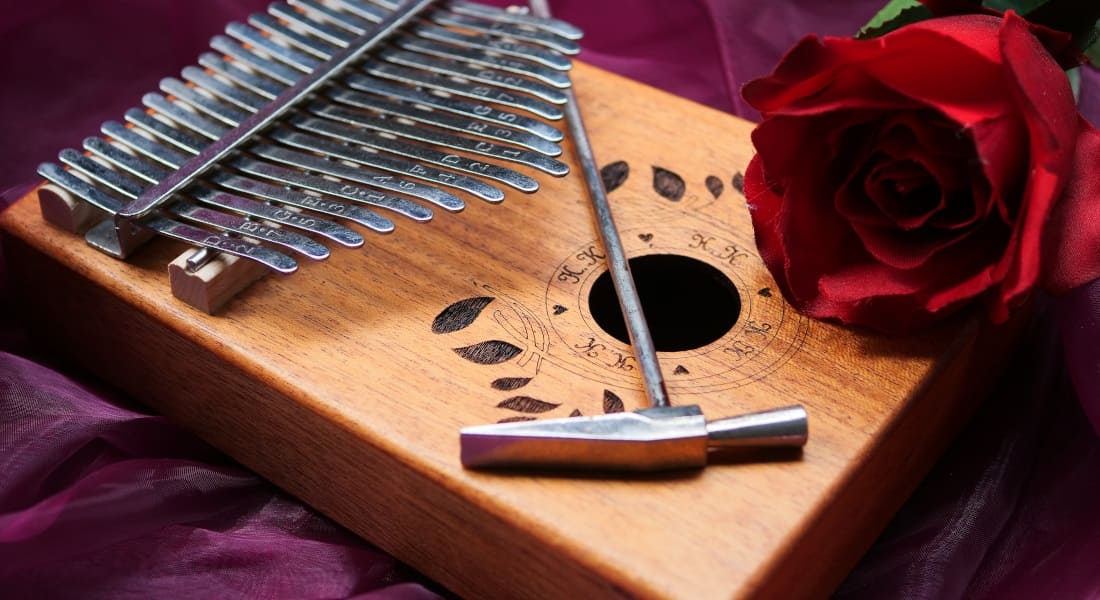 A wooden kalimba with a tuning hammer