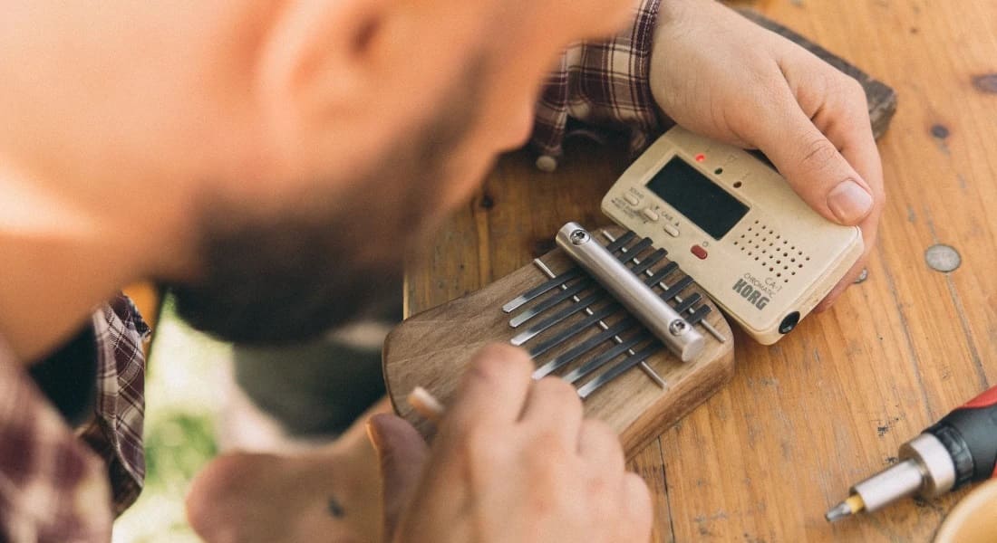 A man tuning his kalimba with a tuner