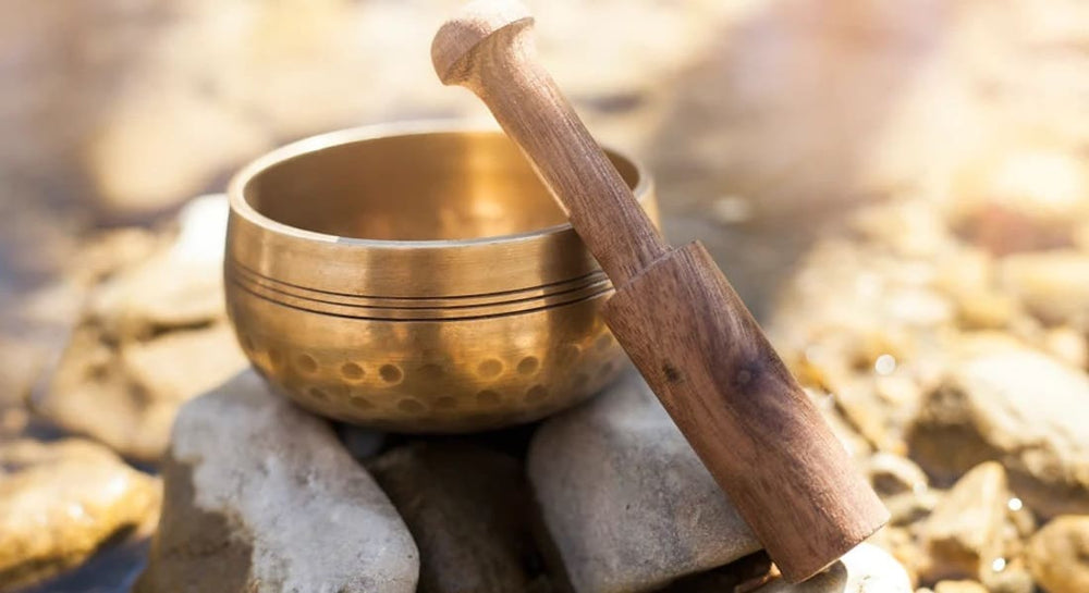 A Tibetan bowl and its mallet placed on a pile of stones