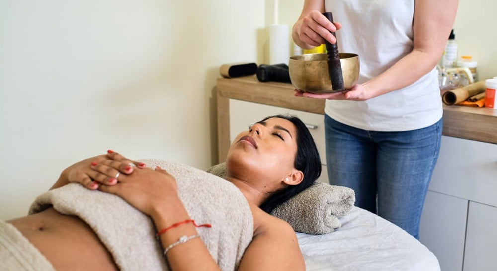 A woman enjoying a guided meditation session with a Tibetan bowl
