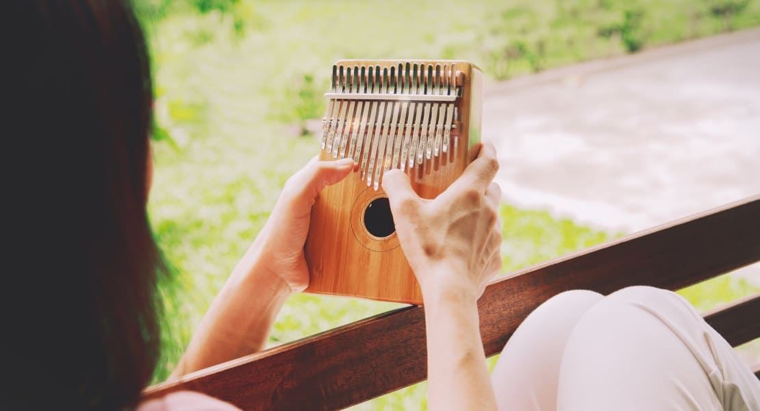 A woman playing a brown kalimba