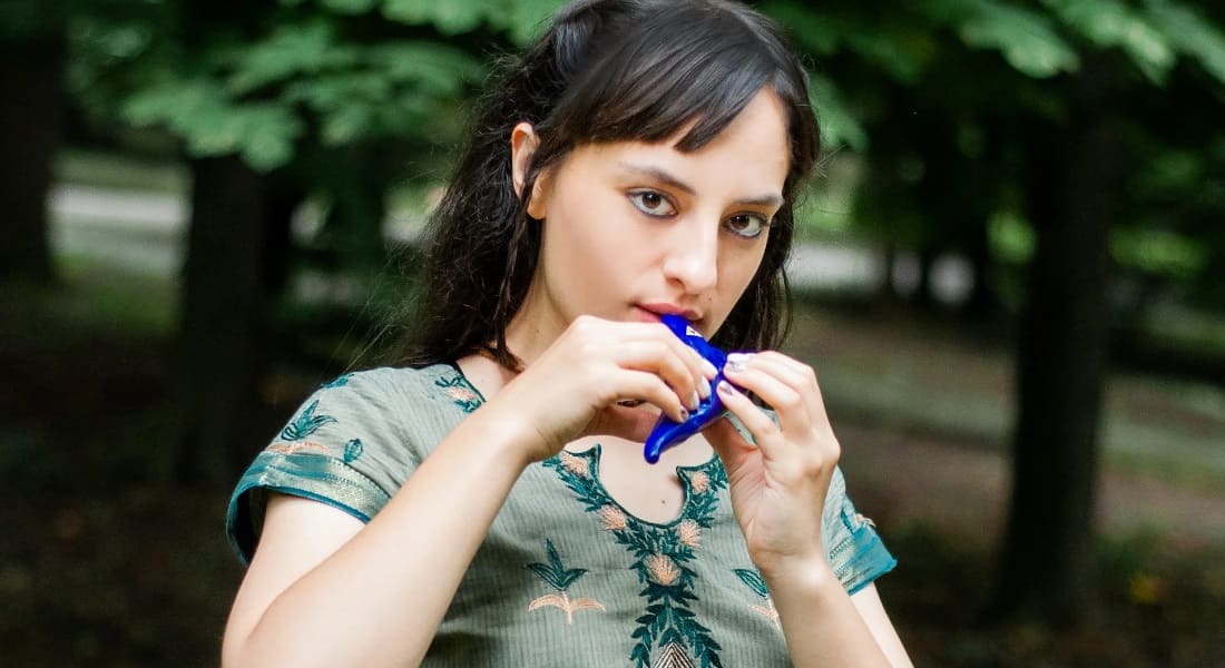 A woman playing a blue ocarina