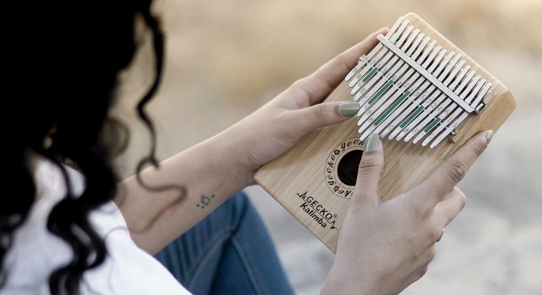 A woman playing a wooden kalimba on the beach
