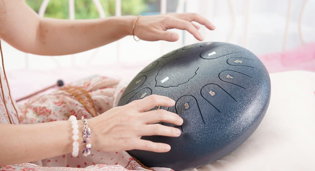 A woman playing a tongue drum with her hands