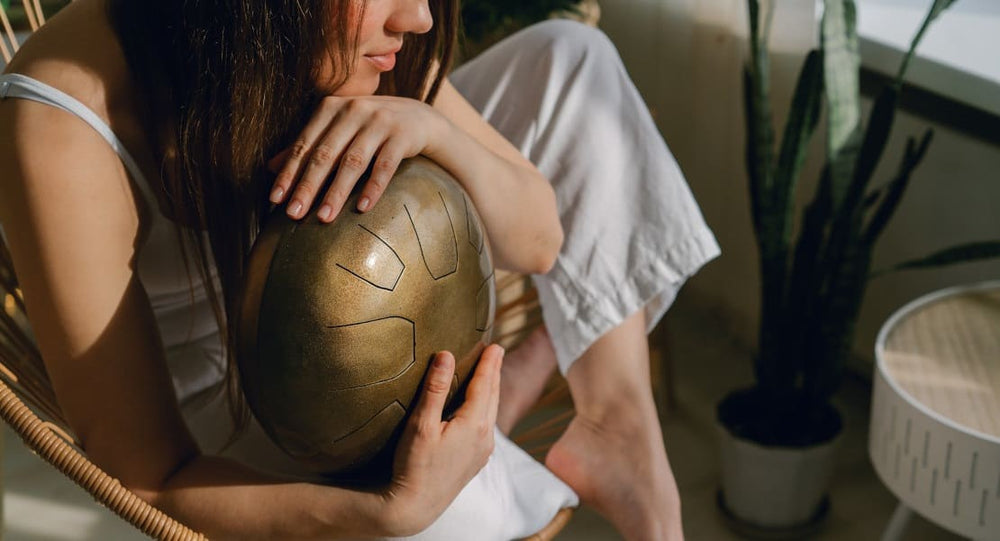 A seated woman holding a tongue drum in her hands
