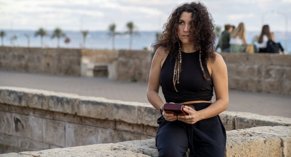 A woman sitting on a low wall playing the kalimba