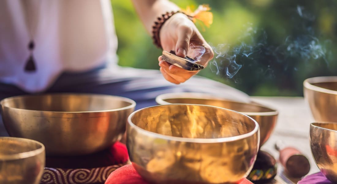 A woman smudging Tibetan singing bowls with incense