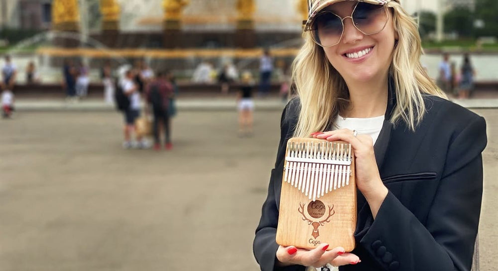 A blonde woman on the street holding a kalimba