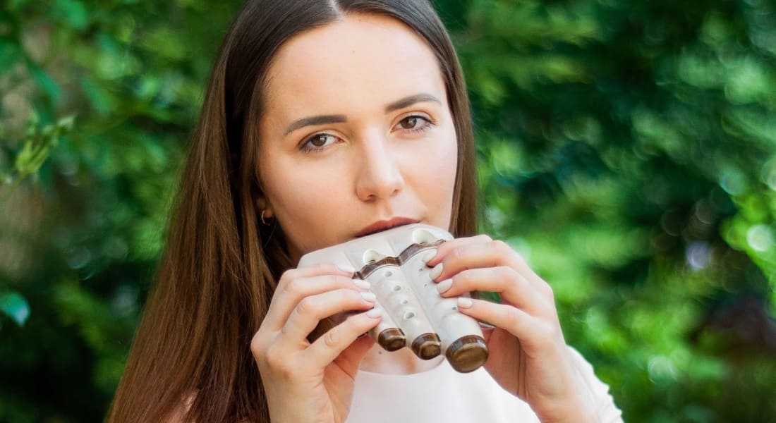A brunette woman playing a triple ocarina