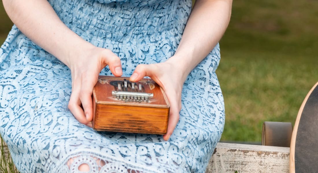 Close-up of a woman in a blue dress playing the kalimba