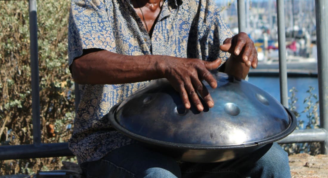 Close-up of a player with a black handpan in the street