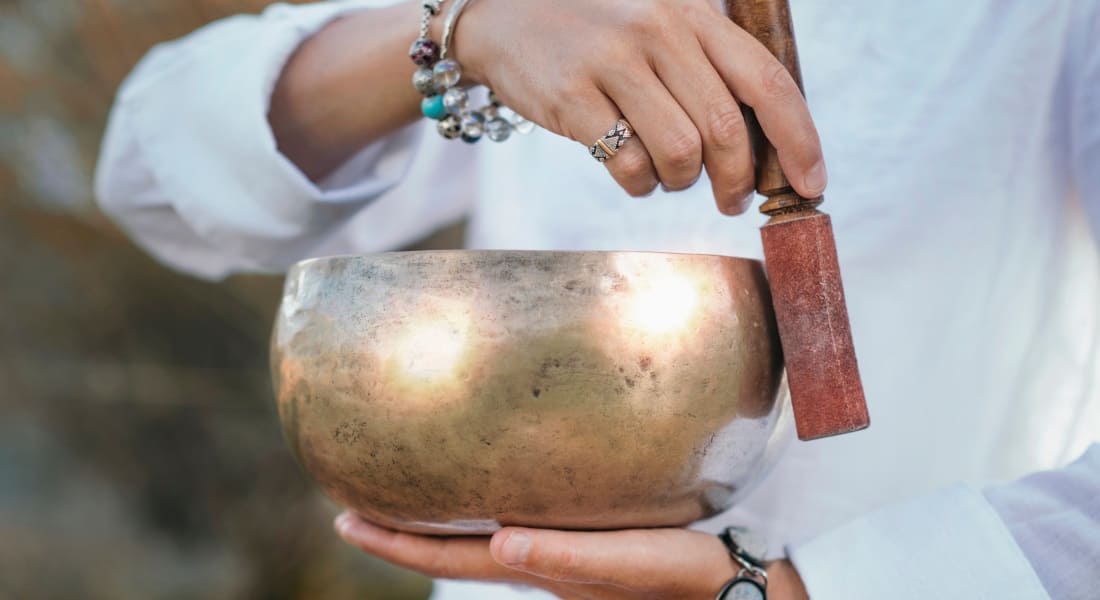 Close-up of a Tibetan singing bowl held by a woman as she makes it sing