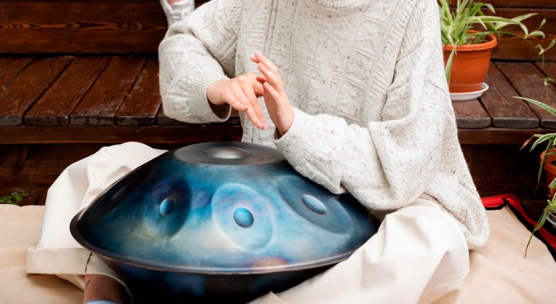Close-up of a woman in a white outfit playing the handpan
