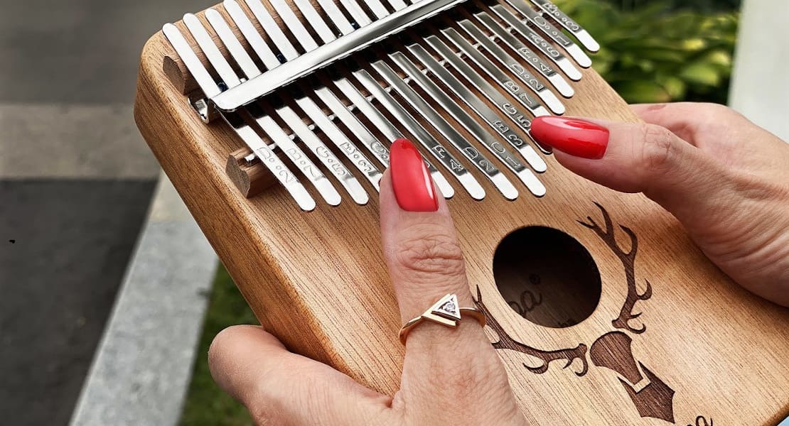 Close-up of a kalimba held by hands with red nails